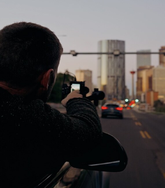 Karl Lee se penchant du côté passager pour photographier l’INFINITI QX55 roulant sur une autoroute