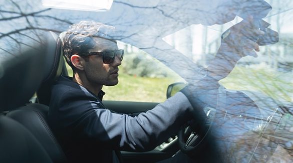 Un homme portant des lunettes de soleil au volant de son véhicule INFINITI