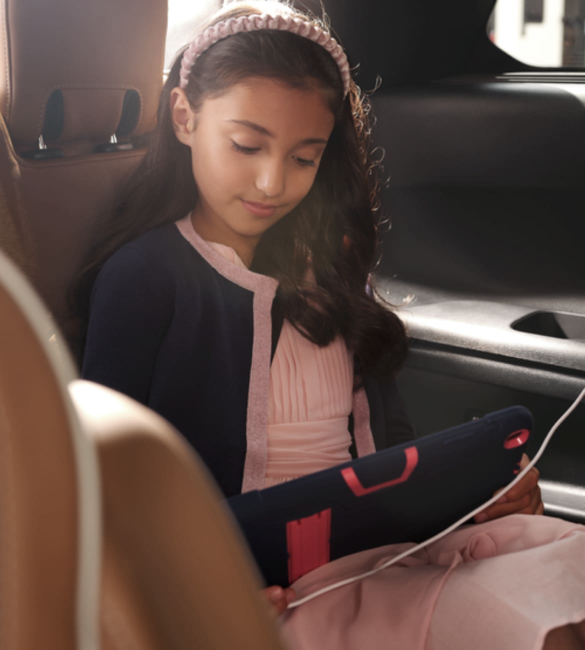 Jeune fille lisant lors d’un voyage en voiture à bord de l’INFINITI QX60 de sa famille 