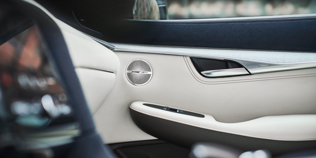 Haut-parleurs Bose montés sur les garnitures en cuir blanc à l’intérieur du panneau de portière du système audio d’un véhicule INFINITI